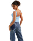 Woman in light blue backless tank top and wide-leg jeans, showcasing casual women's clothing style