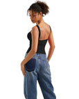 Woman in black backless tank top and wide-leg jeans, stylish women's fashion outfit