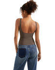 Woman wearing olive green backless tank top with wide straps and blue jeans, showcasing casual women's clothing style