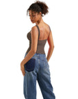Woman in olive green backless tank top and wide-leg jeans, side view