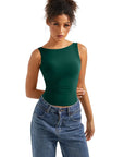 Woman wearing emerald green sleeveless crop top with high-waisted jeans, stylish women's clothing