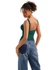 Woman in green backless tank top and wide-leg jeans, side view