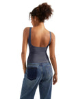 Woman wearing navy blue backless tank top with wide straps, paired with high-waisted denim jeans.