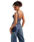 Woman in gray backless tank top and wide-leg jeans, side view