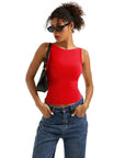 Woman in red sleeveless crop top and blue jeans, wearing sunglasses and black bag