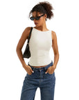Woman in white sleeveless crop top and blue jeans, wearing sunglasses and black bag