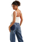 Woman in white backless tank top and wide-leg denim jeans, side view